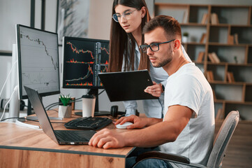 Analyzing information from computer screens. Two stock brokers is working together in the office with finances