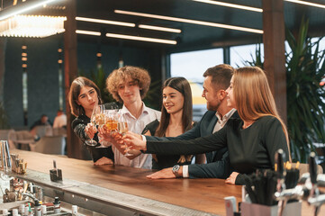 Wall Mural - Sitting together. Group of people in elegant clothes are in the restaurant celebrating event