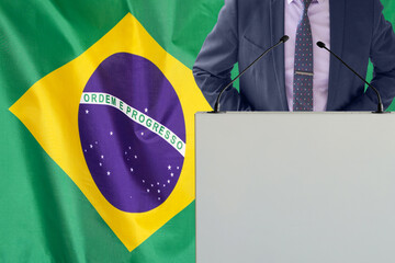 Tribune with microphone and man in suit on Brazil flag background. Businessman and tribune on Brazil flag background. Politician at the podium with microphones background Brazil flag. Conference