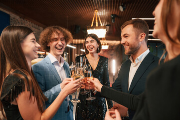 Wall Mural - Talking and having fun. Group of people in beautiful elegant clothes are celebrating New Year indoors together