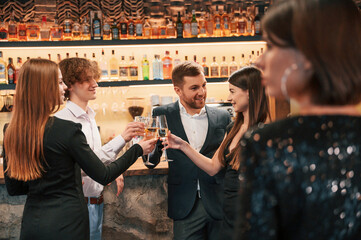 Wall Mural - Talking, smiling, having fun. Group of people in beautiful elegant clothes are celebrating New Year indoors together