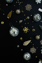 Wall Mural - Golden confetti and Christmas tree balls on black background. Flat lay, top view Christmas holidays background