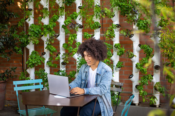 Smiling young ethnic men, dressed in casual clothes, in a green area in nature against the backdrop of a smart garden with modern hydroponic systems. Sustainable environment green space for work