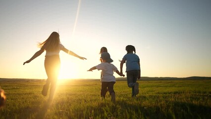 Wall Mural - happy family. people in the park. children child running together in the park on the grass silhouette. daughter and son are running. happy family and little child in summer. concept dream sunset