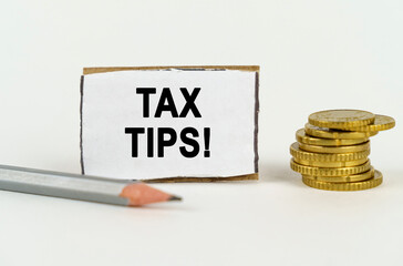 Wall Mural - On a white background, a pencil, coins and a sign with the inscription - Tax Tips