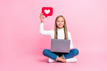 Poster - Full size photo of positive schoolkid sit floor arm hold paper like card use netbook isoated on pink color background