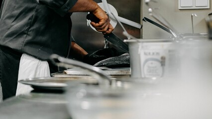 Wall Mural - Closeup of a chef cutting fish in the kitchen