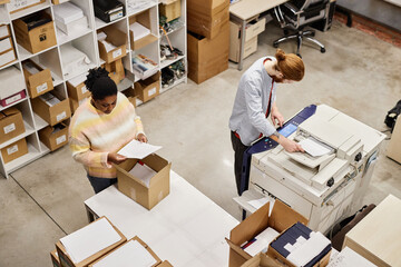 Top view of two workers using copying machine at printing factory, copy space