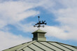 Weather vane in the form of a canoe against the blue sky.