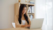 © Monster Ztudio - Young asian woman working at home. Female using computer laptop on desk at house