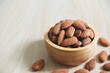 Almonds in brown wooden bowl on wooden table background