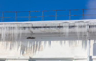 Wall Mural - Icicles hang from the roof of the house.