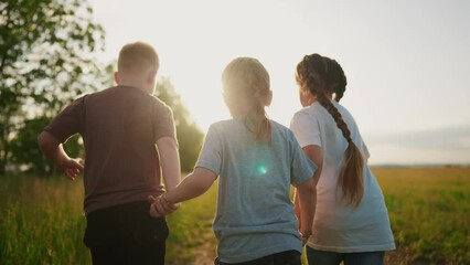 Wall Mural - children running in the park holding hands. happy family kindergarten kid dream concept. team of children hold hands run work as a lifestyle team. children kid run in the park