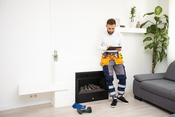 Service technician with tablet repairing a fireplace in a home