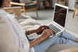 © New Africa - Young woman working with laptop on sofa at home, closeup
