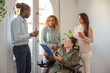 © Renata Hamuda - a a businesswoman in a wheelchair with a disability discuss business strategy with her multiracial colleagues near to the window