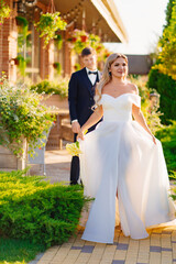 Wall Mural - groom and bride in traditional wedding clothes kiss in park. selective focus 