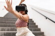 © VISTA by Westend61 - Young woman wearing virtual reality simulator gesturing on staircase