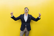 © VISTA by Westend61 - Cheerful businessman making thumbs up gesture standing against yellow wall