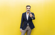 © VISTA by Westend61 - Smiling businessman showing thumbs up gesture against yellow wall