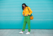 Woman Carrying Oranges In Mesh Bag By Blue Wall