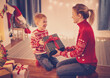 © candy1812 - Mother and son indoors sitting on the floor and giving present box each other in Christmas eve.