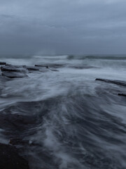 Wall Mural - Wave water flowing between rocks on the shore.