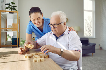 Wall Mural - Nurse in retirement home helping old male patient with puzzle. Senior man with cognitive disorder sitting at table in geriatric clinic, playing games and thinking. Dementia, Alzheimer's, care concept