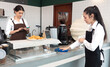 © Nassorn - Young barista and waitress women are standing at cafeteria counter bar preparing orders and cleaning. Two lesbian women couple manage a small coffee shop business together. LGBTQ lifestyle.