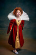 © master1305 - Portrait of little red-headed girl, child in costume of royal person isolated over dark green background. Grimacing