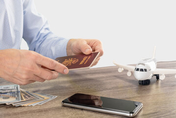 Wall Mural - Male traveler giving his passport for security checkpoint and registration for flight, inscription European Union Spain passport, on a light gray studio background