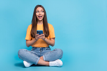 Sticker - Photo of excited impressed young lady wear yellow t-shirt typing modern device looking empty space isolated blue color background