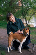 Portrait of a woman with a Basenji dog in nature