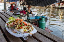 The Spicy Vietnamese Sausage Salad On Dish With Blurred Kitchen On Boat At Background, Khlong Lat Mayom Floating Market, Thailand.