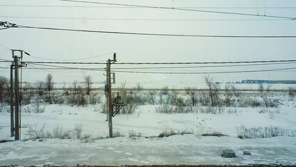 Wall Mural - Snow-covered landscape is visible from the window of a passing train