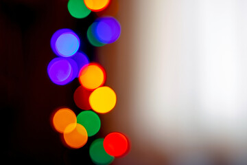 Wall Mural - Abstract background with colorful bokeh from a garland in a dark room near a window