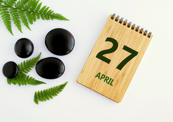 Wall Mural - April 27. 27th day of the month, calendar date. Notepad, black stones, green leaves. Spring month, the concept of the day of year