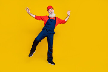 Wall Mural - Photo of cheerful good mood senior guy dressed uniform overall red hardhat having fun dancing isolated yellow color background