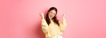 Girl screams with joy and fist pump, say yes, achieve goal or success, celebrating achievement, triumphing and winning, standing over pink background