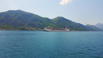 Wall Mural - Aerial video. A big cruize ship is moving through the Boka Kotor Bay. Summer in Montenegro. Slowmotion shot
