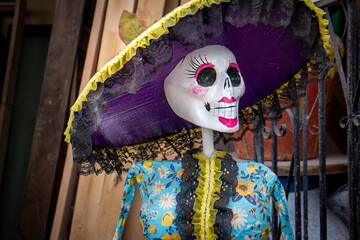 Skeleton statue with sombrero with wooden doors in the background