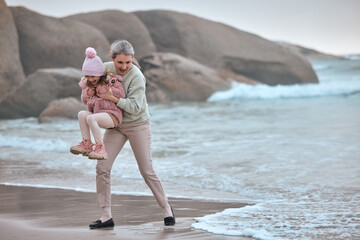 Grandmother, child and beach fun while on vacation for bonding, love and care while playing with water or waves. Senior woman and girl kid happy about travel, adventure and quality time at sea