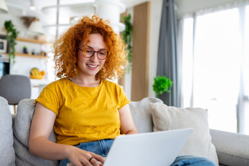 Woman sitting with computer on sofa, studying at home, e-learning and remote freelance job concept