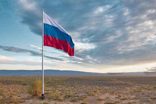 The waving Russian flag is set in the steppe against a dramatic sky with clouds and empty space for text. Border demarcation concept. State flag of the Russian Federation