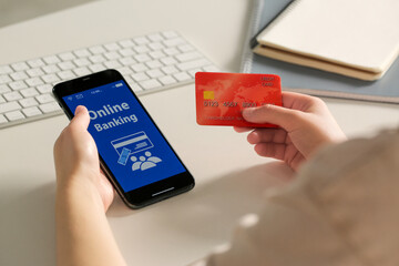 Woman using online banking app on smartphone and credit card at white office table, closeup