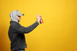 Handsome man holding can of spray paint on yellow background. Space for text