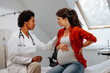 © bernardbodo - Doctor advising pregnant woman at hospital.