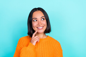 Sticker - Portrait of gorgeous nice woman bob hairstyle wear orange sweater finger on cheek look empty space isolated on turquoise color background