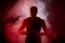 Basketball Player Side Lit With Red Color Holding A Ball Against Smoke Background. Serious Concentrated African American Man..
