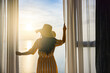 © shine - Rear back view woman opening curtains, relaxing and looking beautiful seascape panorama with rays of sun light in holiday on the balcony in high quality hotel feeling happy. Composition of nature